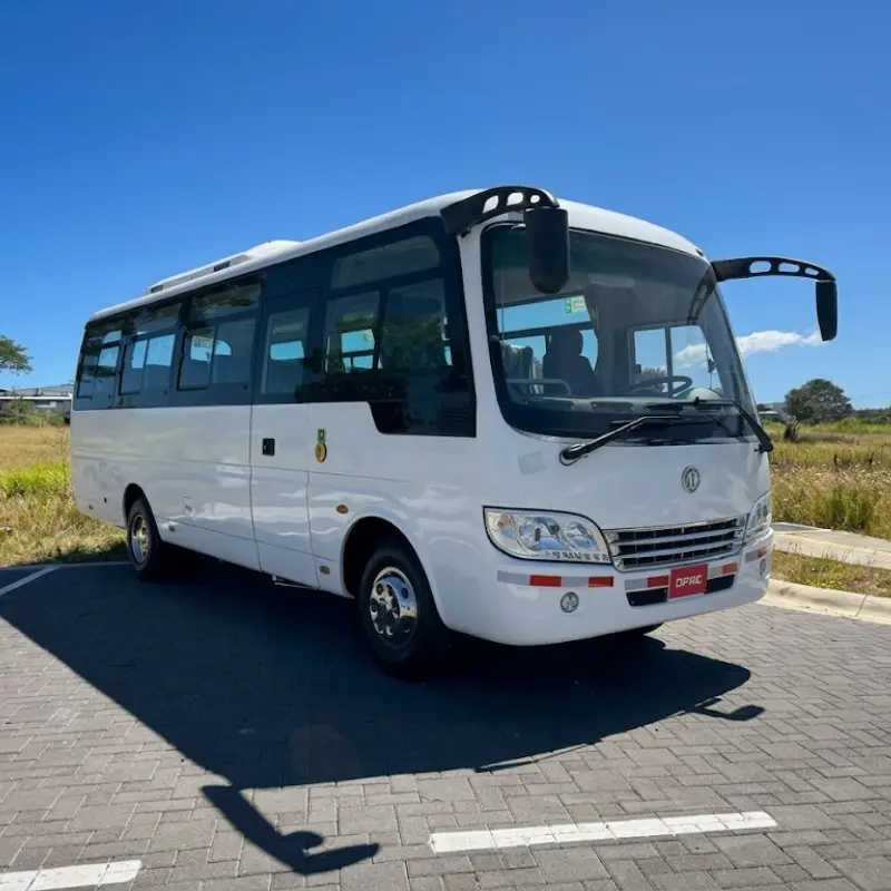 White DFAC executive minibus for large groups parked on a paved driveway under a clear blue sky in Costa Rica.